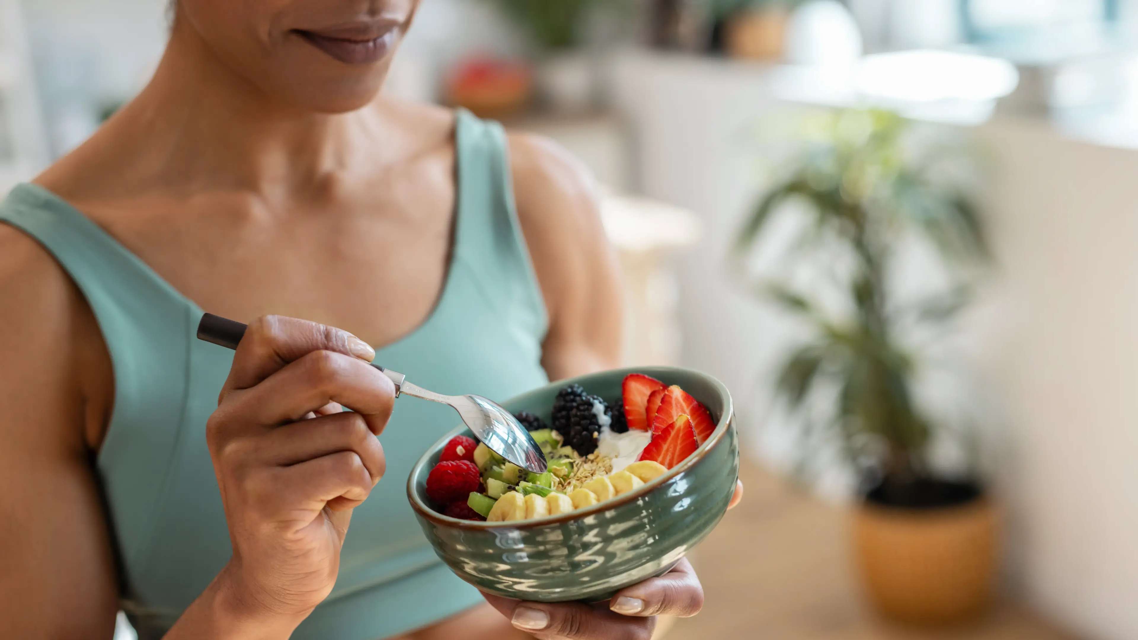 Eine Frau ist Obst aus einer Schüssel