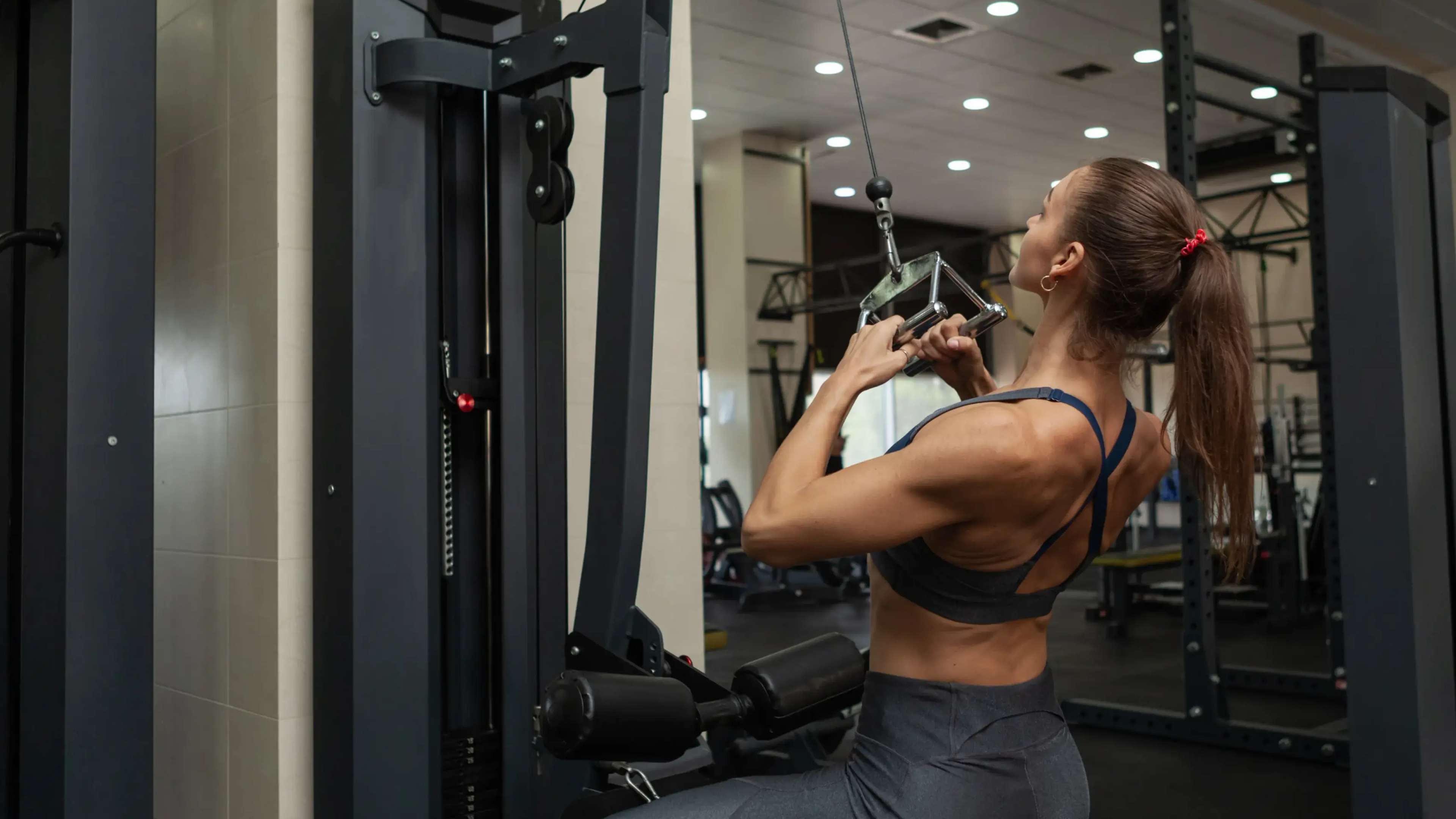 Eine Frau macht enges Latziehen mit Parallelgriff im Fitnessstudio