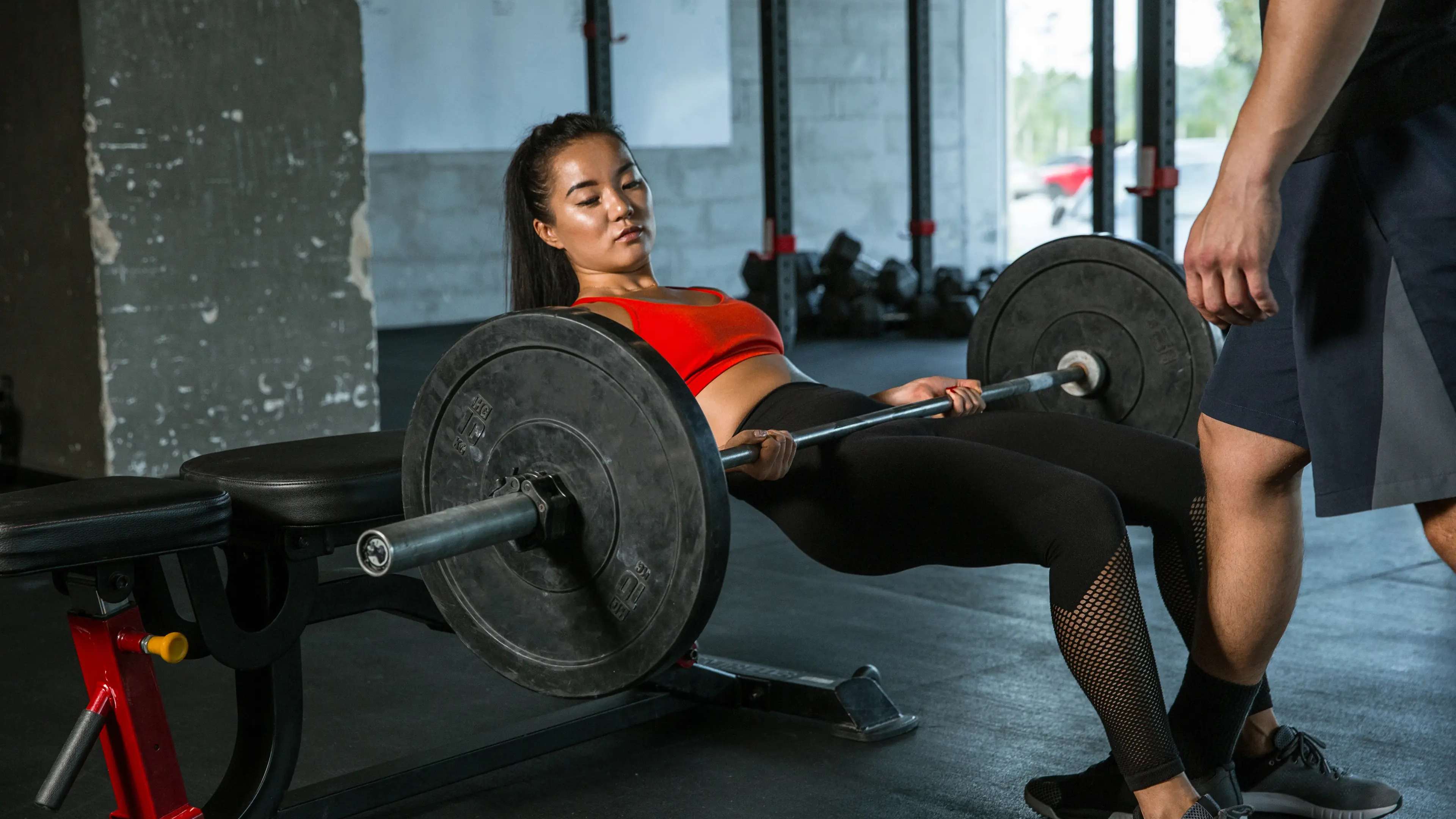 Eine Frau macht einen Hip Thrust mit Langhantel im Fitnessstudio