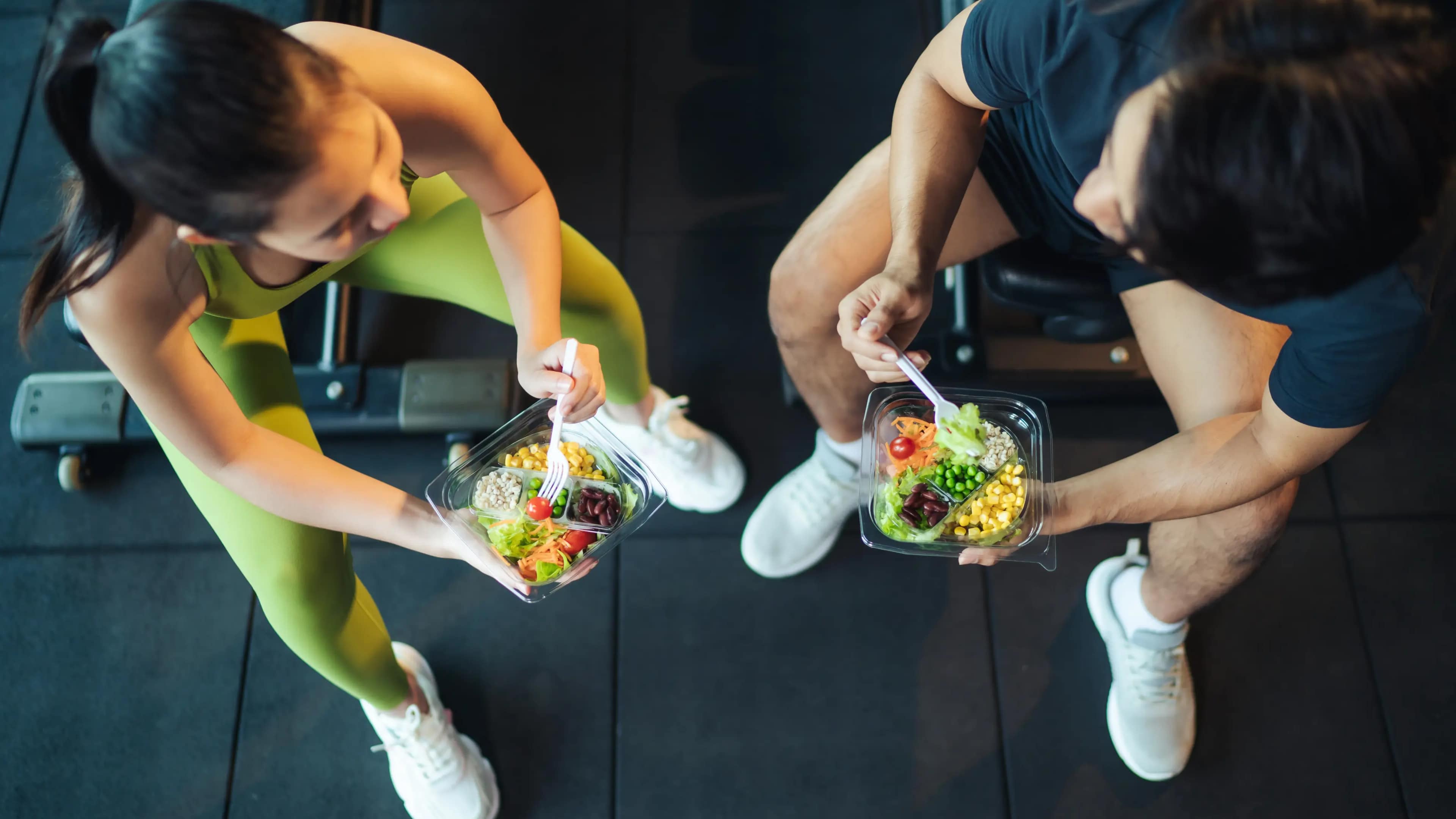 Ein Paar isst Salat im Fitnessstudio