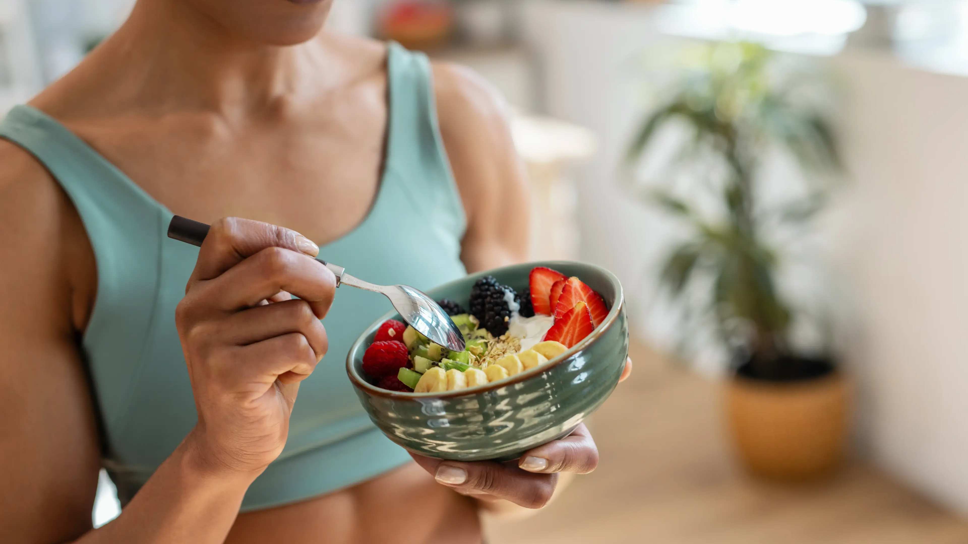 Eine Frau isst Joghurt mit Obst aus einer Schale