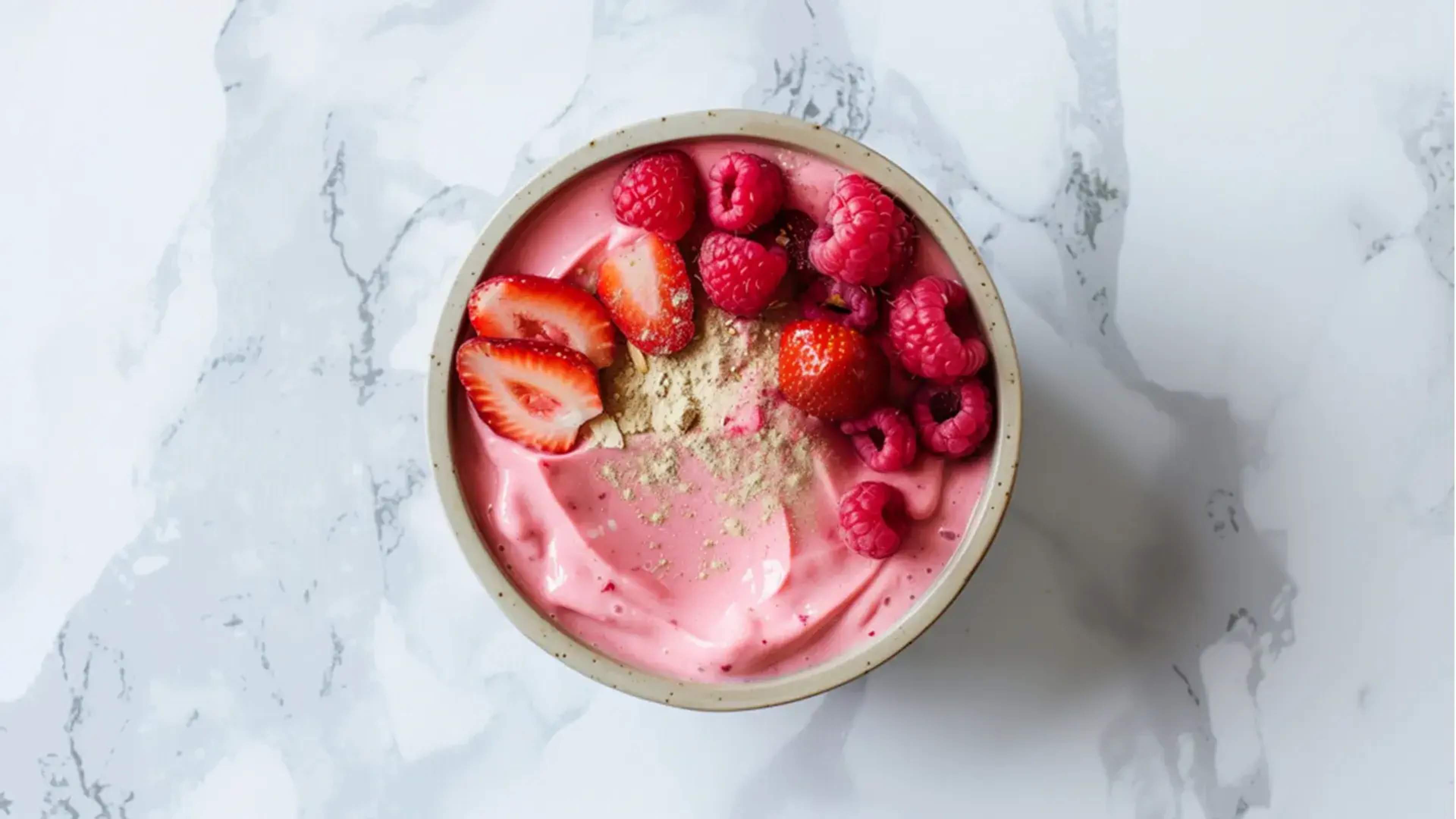Ein rosafarbener Pudding mit Beeren in einer Schale auf einem Marmortisch