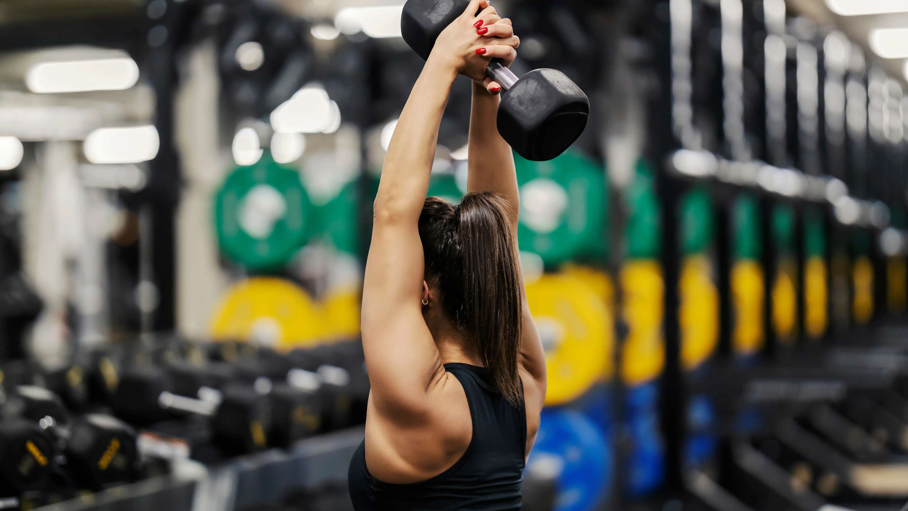 Eine Frau macht Tricep Overhead Extensions mit einer Kurzhantel
