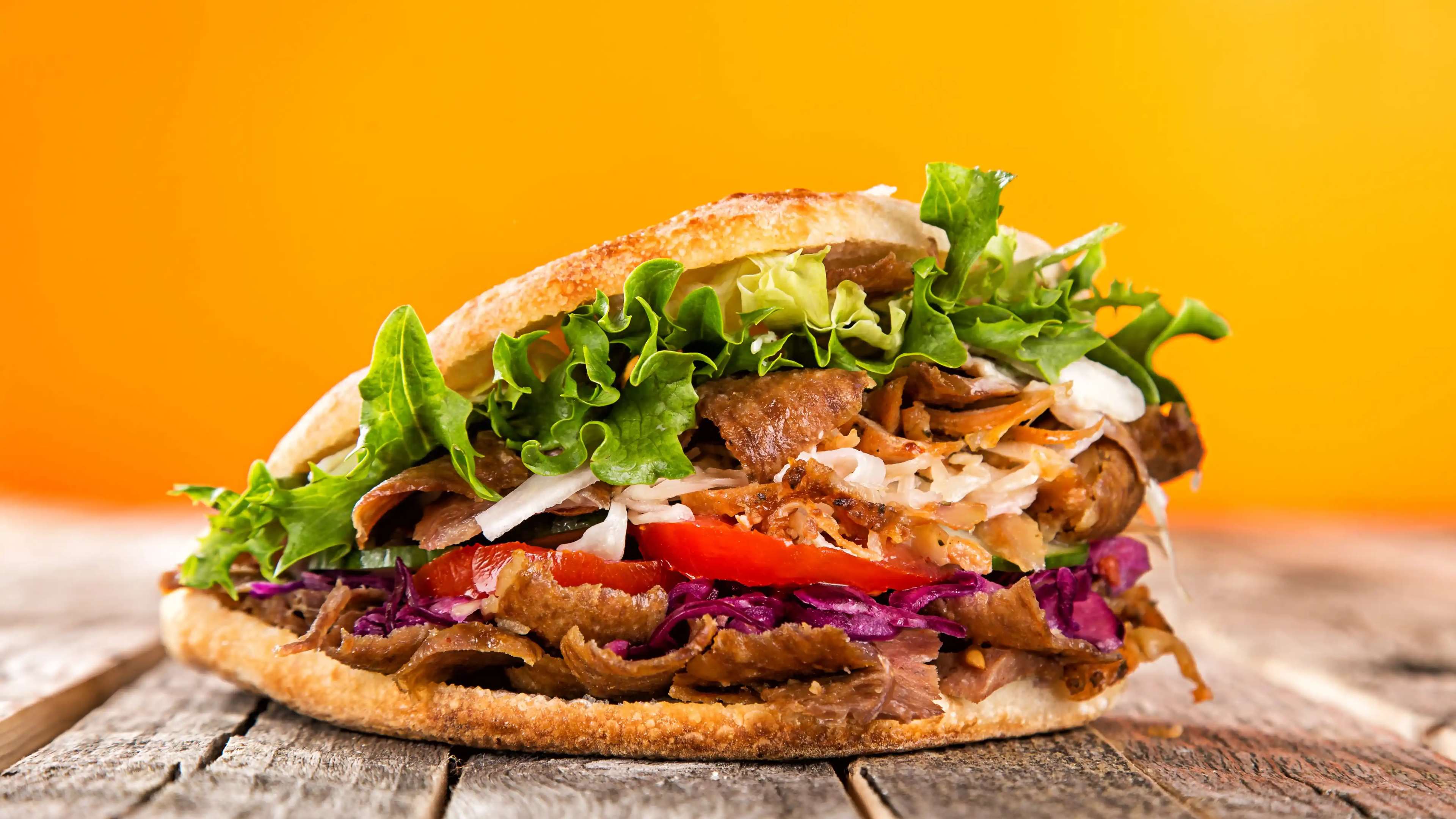 Ein Döner auf einem Holztisch vor gelbem Hintergrund