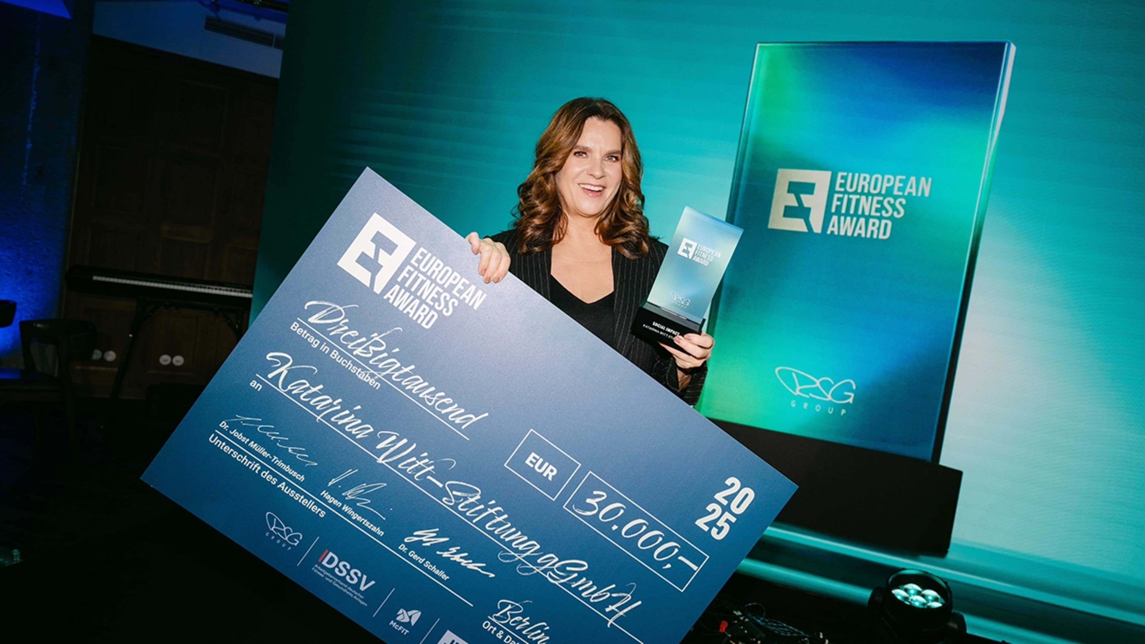 Katarina Witt hält einen Scheck und den European Fitness Award