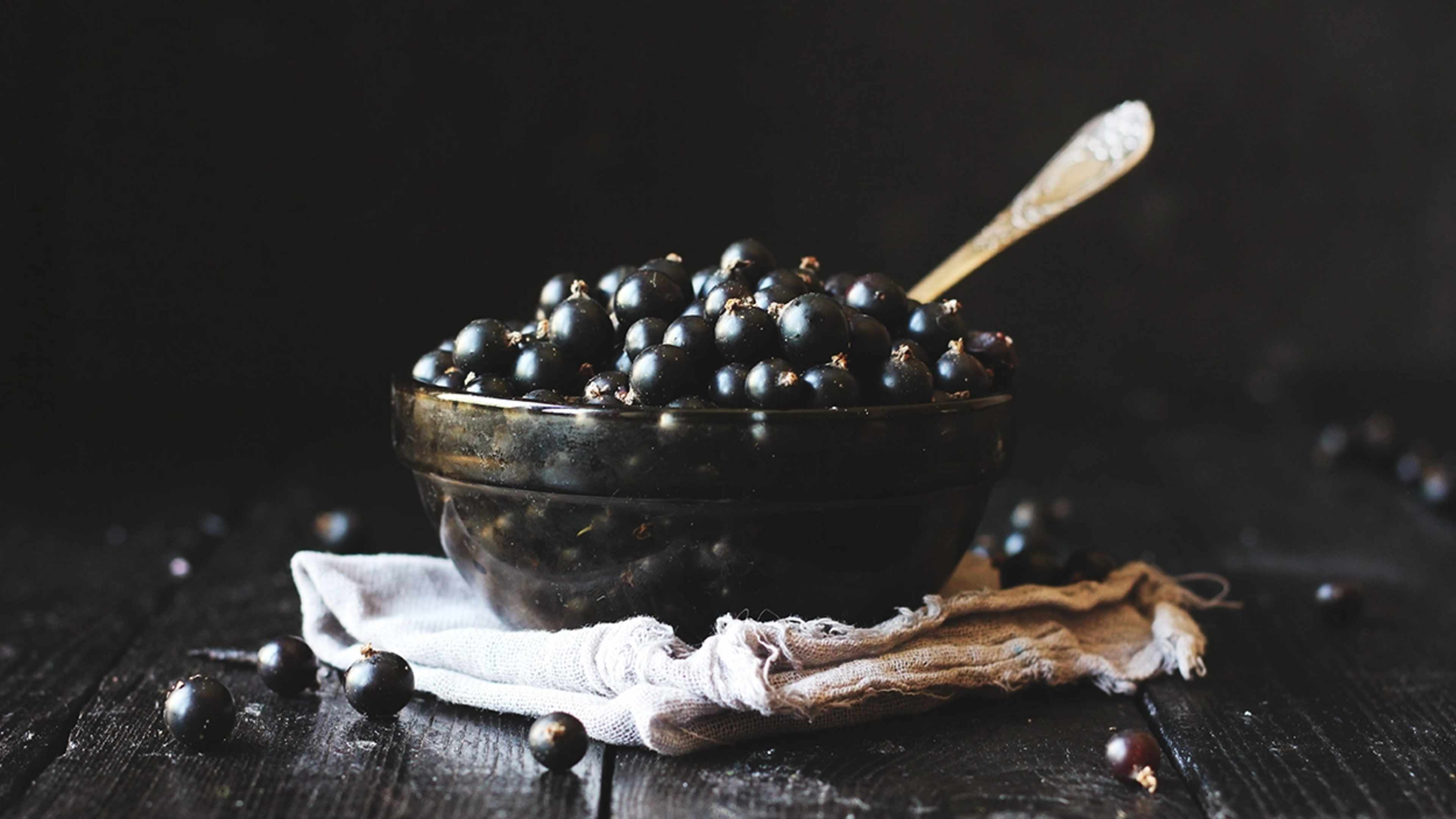 Schwarze Johannisbeeren in einem Schüsselchen mit einem Löffel