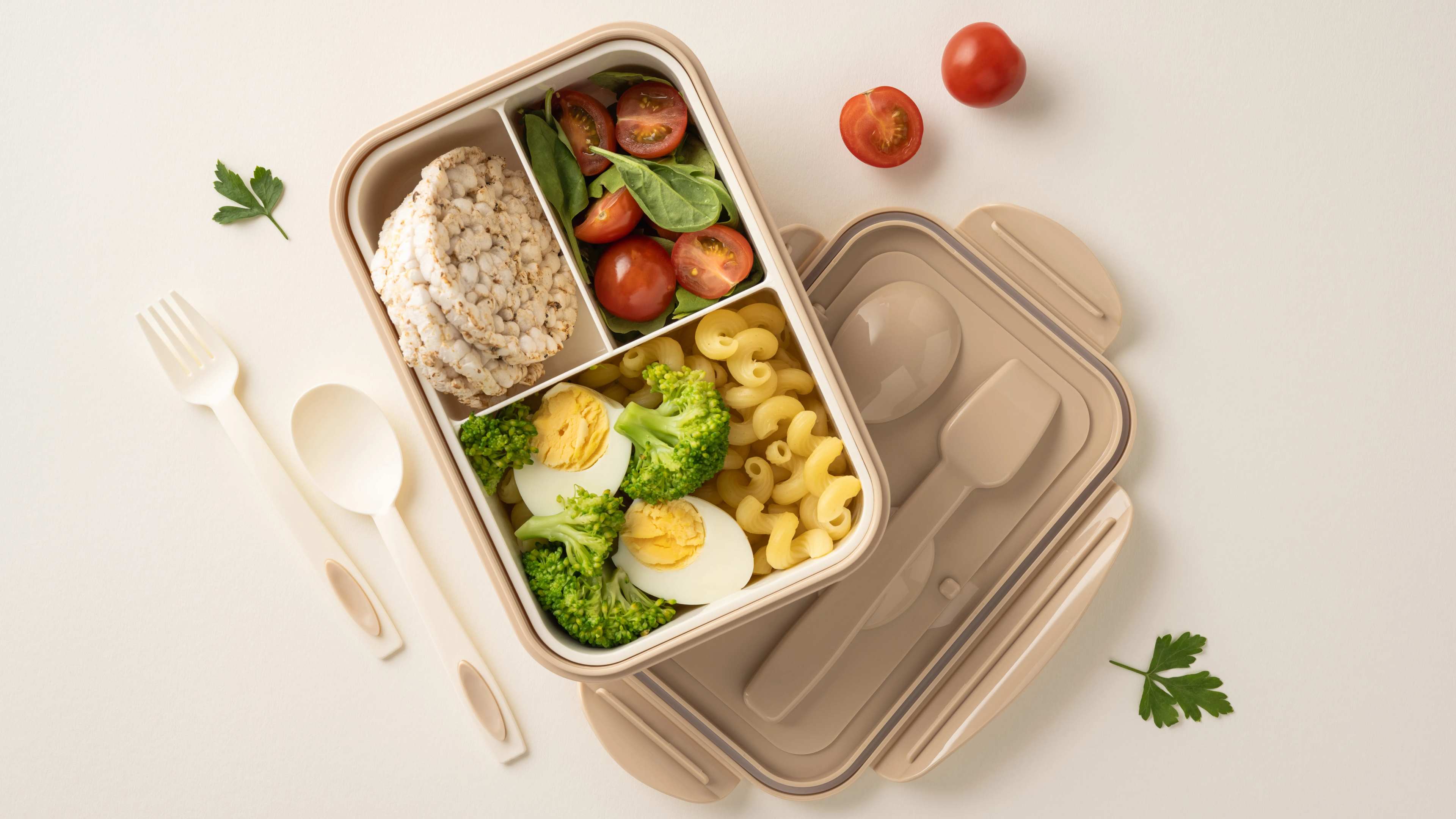Eine Brotdose mit Essen neben Besteck