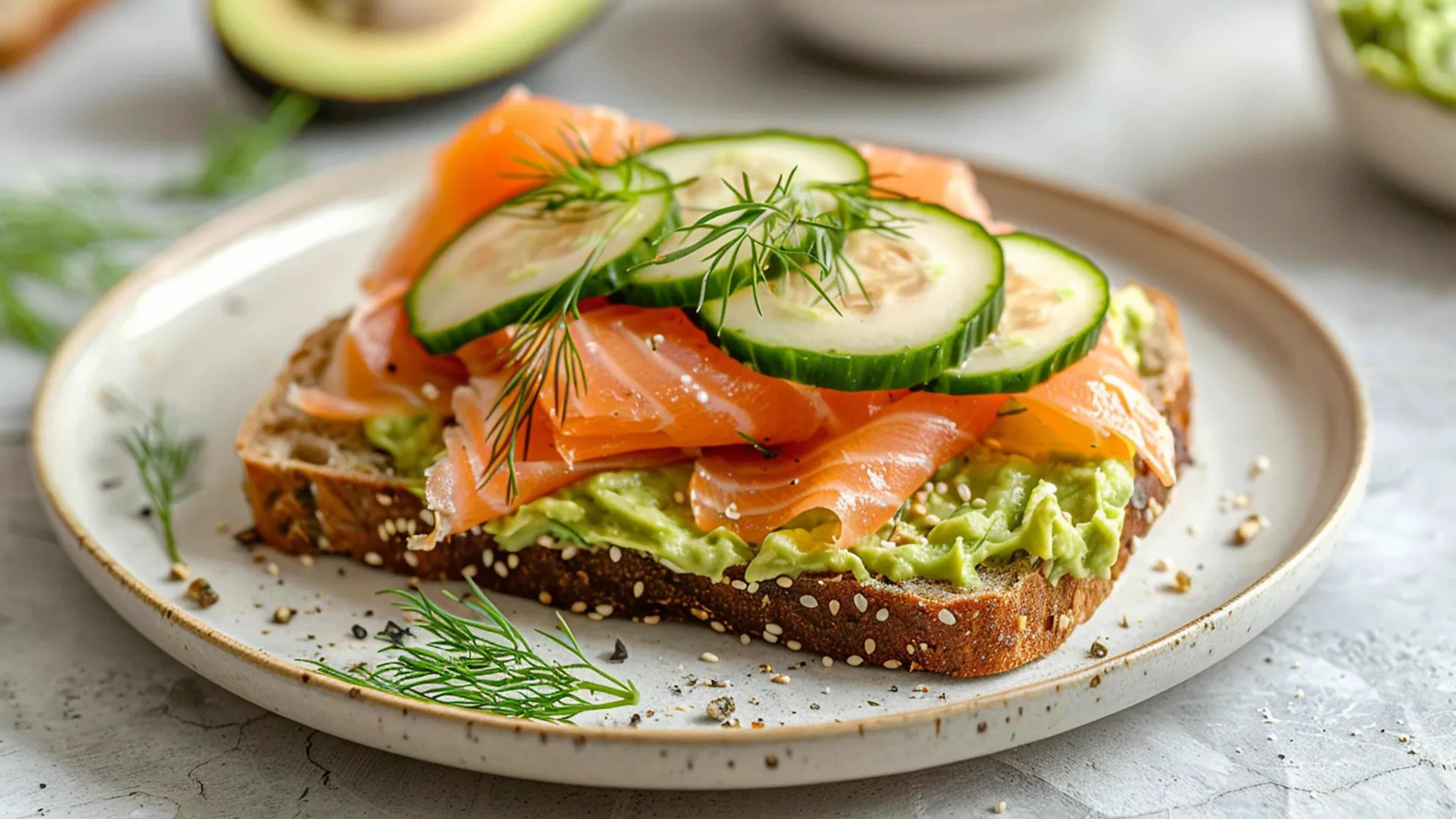 Eine Scheibe Vollkornbrot mit Räucherlachs, Avocado und Gurke