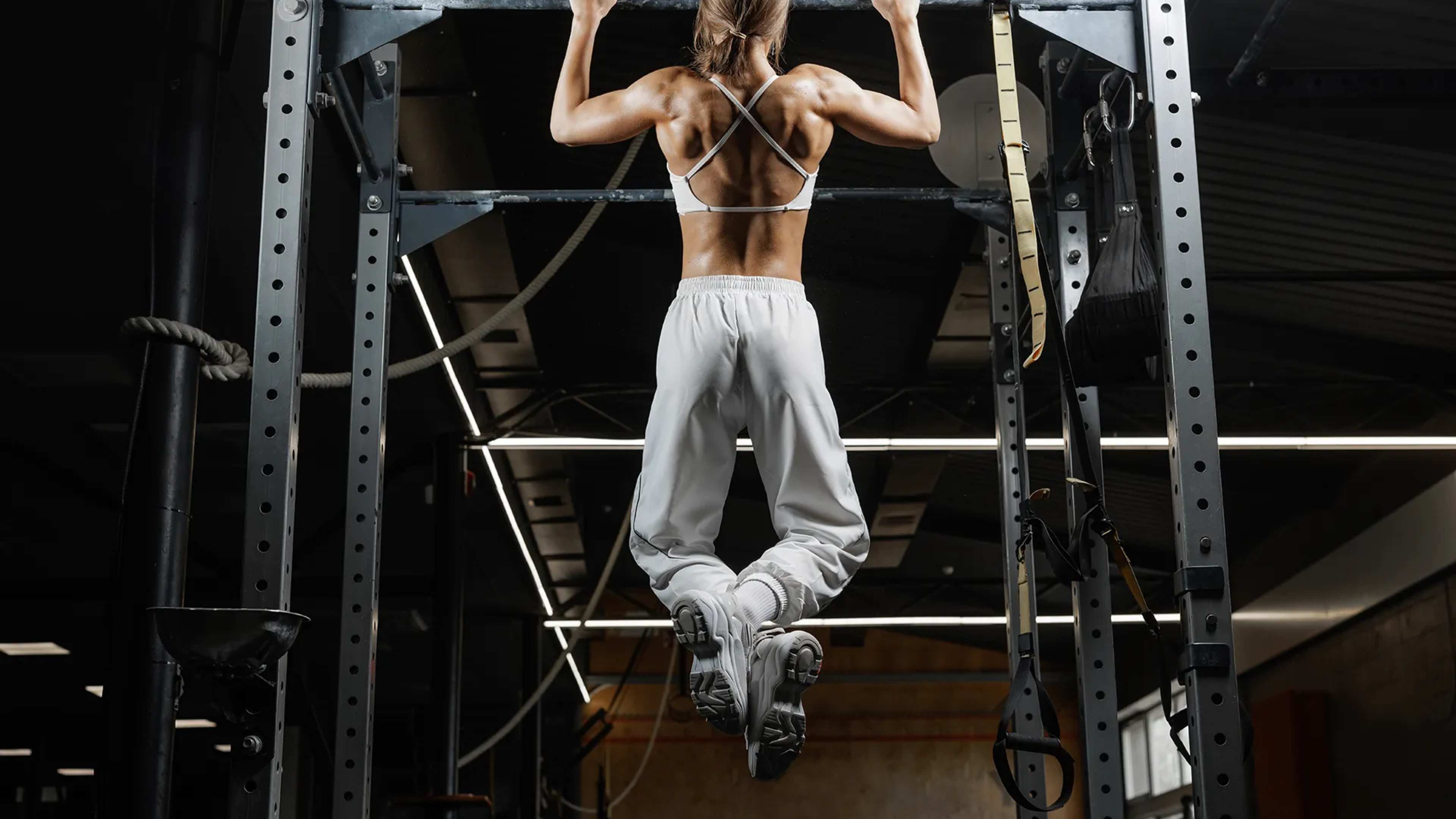 Eine Frau macht einen Klimmzug im Fitnessstudio