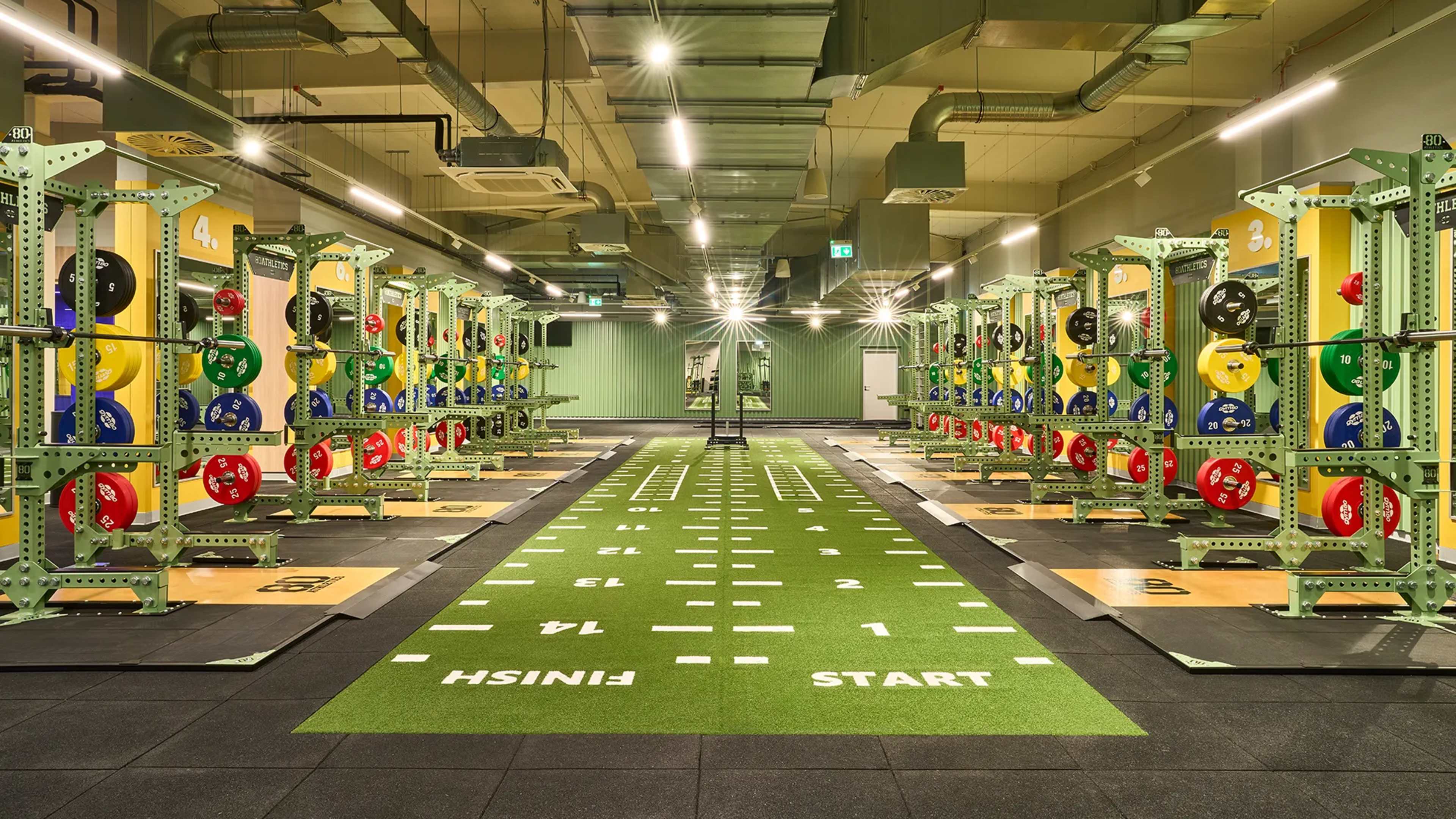 Mehrere Racks und Kunstrasen in einem modernen Fitnessstudio