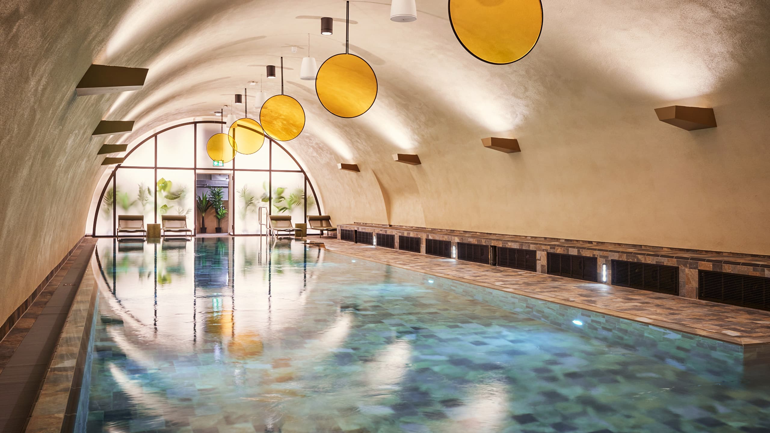 Der Pool in einem Raum mit gewölbter Decke und gelben, runden Dekoelementen im John Reed Fitness Studio Berlin Bötzow.